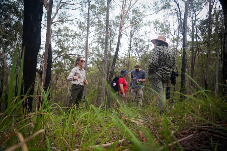 A woman speaks to people in bushland