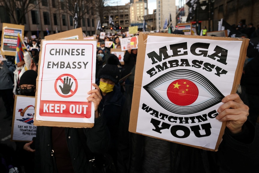 People hold signs expressing concern about a Chinese embassy at a protest