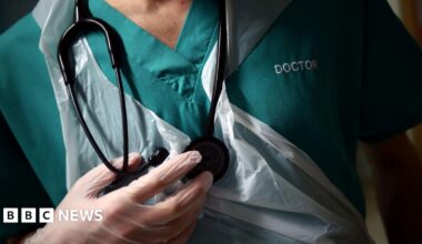 A picture of a doctor. He is wearing a green shirt and is wearing see-through gloves.