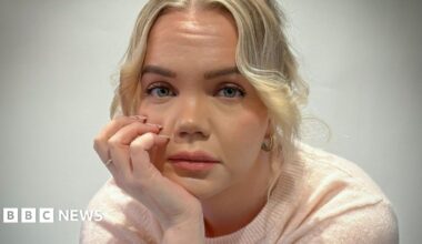 Meri-Tuuli Auer looking towards the camera, she is seated with her head resting in her hand. She has blonde hair and is wearing a light pink short sleeved woollen top.
