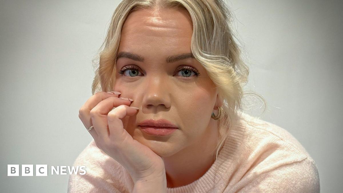 Meri-Tuuli Auer looking towards the camera, she is seated with her head resting in her hand. She has blonde hair and is wearing a light pink short sleeved woollen top.