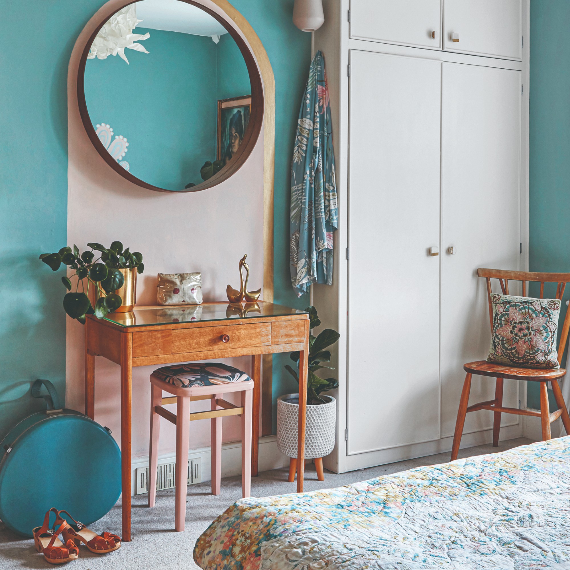 A blue-painted bedroom with a pink arch zoning a dressing table with an upholstered pink stool