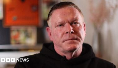Prime Minister Mark Carney, wearing a black suit jacket, and a white button-up shirt leans his chin on his hands. He has short grey and black hair and is looking away from the camera.