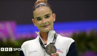 Alice Kinsella does a split leap on beam