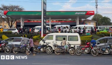 Donald Trump and Keir Starmer sit in a formal drawing room setting  on arm chairs with US and UK  flags behind them. Both have serious expressions and are looking out and not at each other.