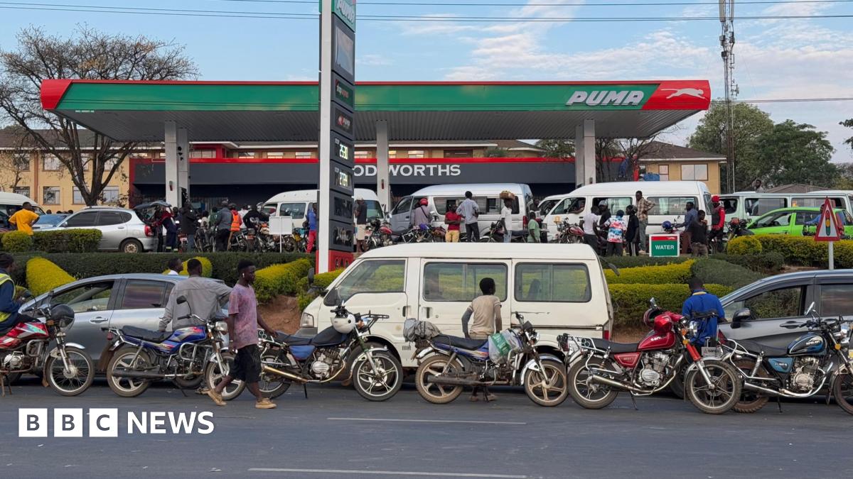Donald Trump and Keir Starmer sit in a formal drawing room setting  on arm chairs with US and UK  flags behind them. Both have serious expressions and are looking out and not at each other.