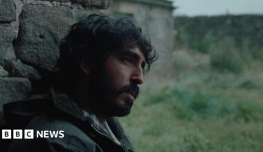 A man sat against a wall staring ahead