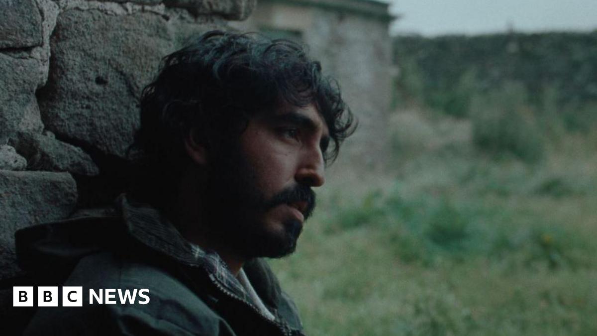 A man sat against a wall staring ahead