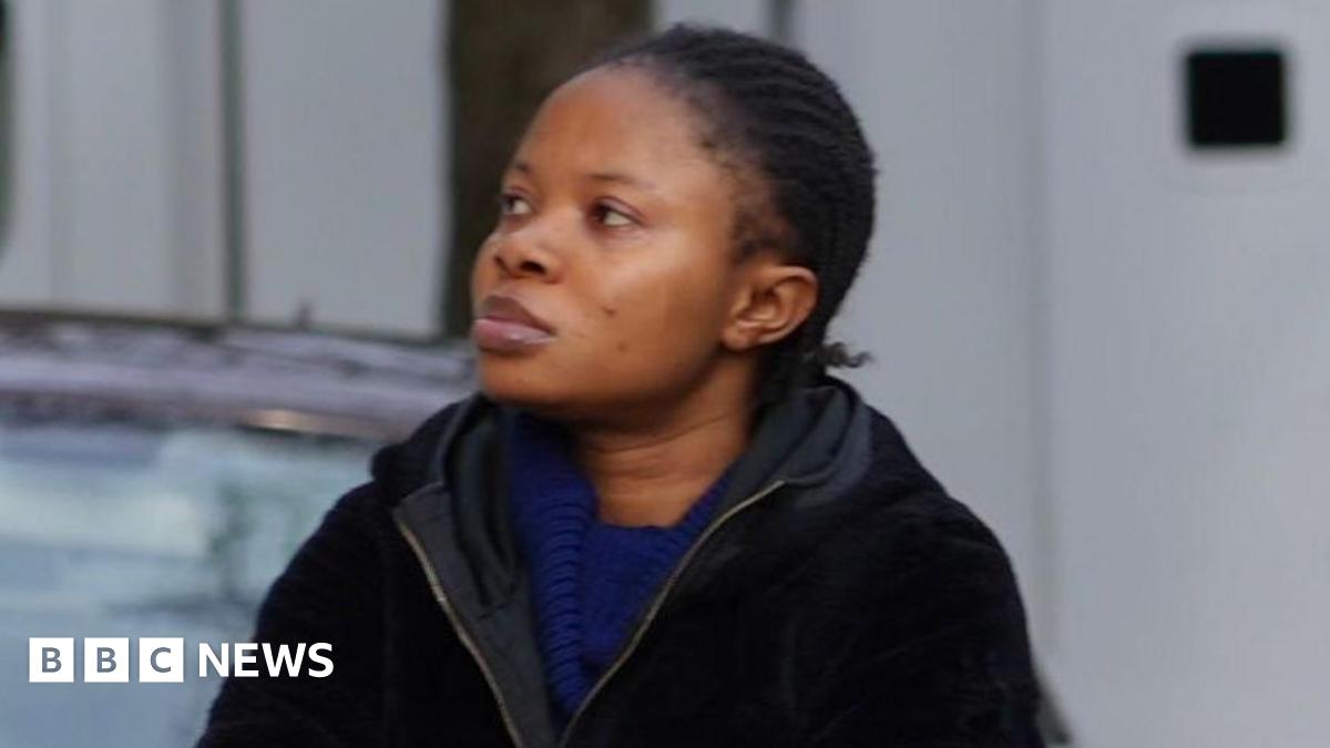 A woman wearing a blue dress and a black jacket has her arms folded as she is walking by the steps to the court.