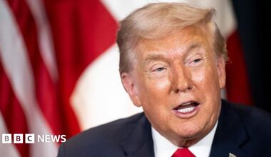 A close-up image of Canadian Prime Minister Mark Carney looking towards the left direction. He has blue eyes and short, grey hair. Behind him is a blue backdrop with a blurred out World Economic Forum logo.