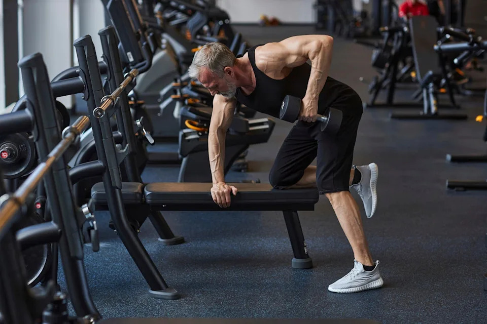 mature man working out with dumbbell in health club