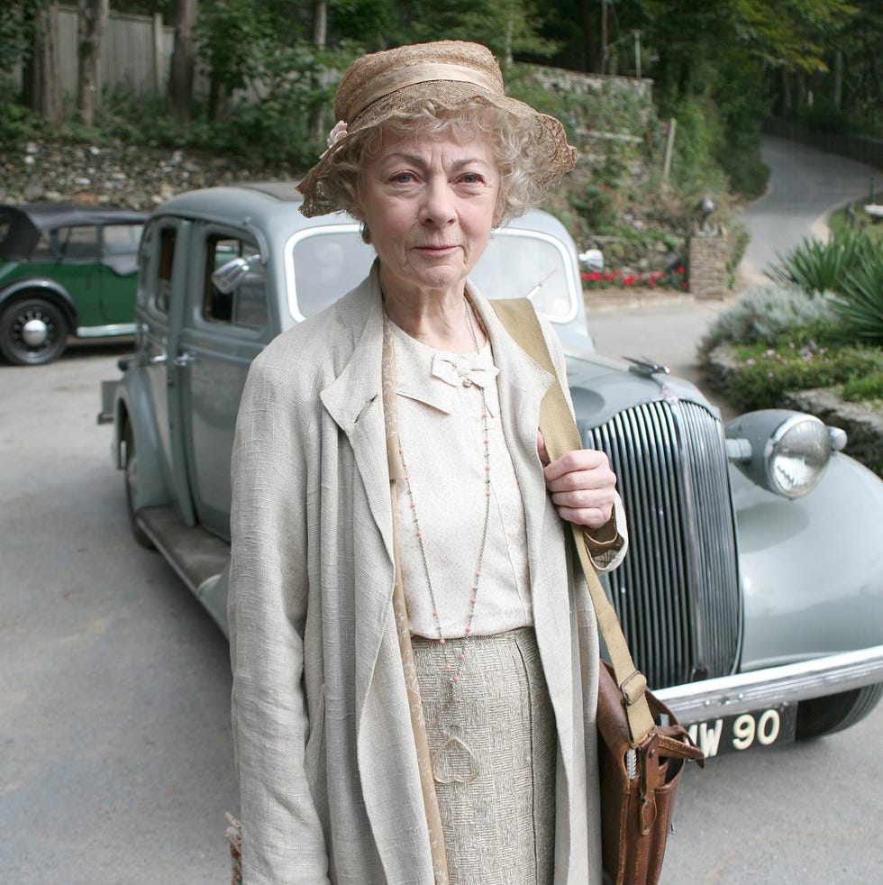 woman standing in front of classic cars