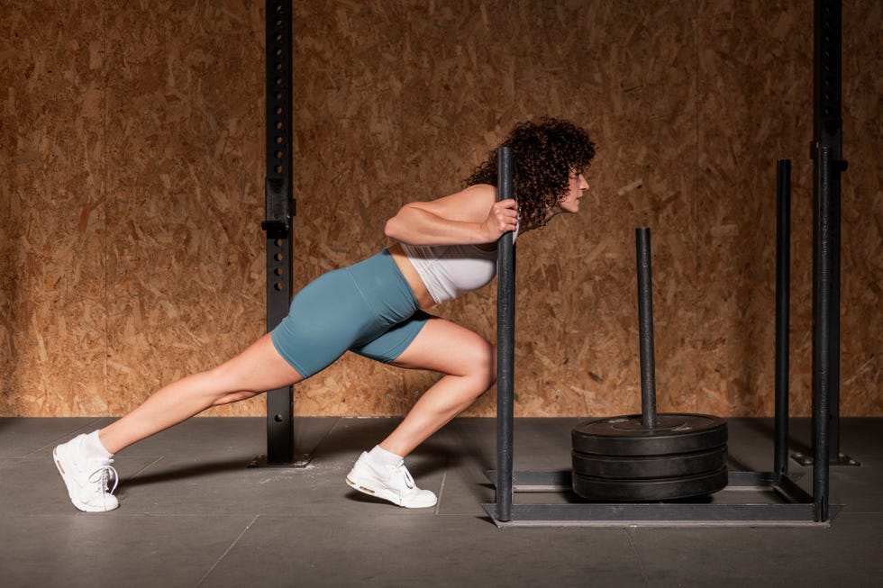 person performing a sled push exercise in a gym