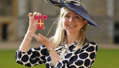 Dr Melanie Ivarsson smiles and holds up her OBE medal after an investiture ceremony at Windsor Castle.