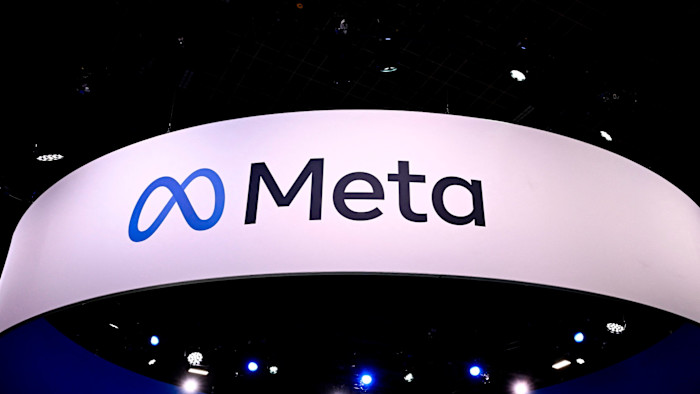The Meta logo is displayed on a large white sign at a technology fair, with blue stage lights visible below.