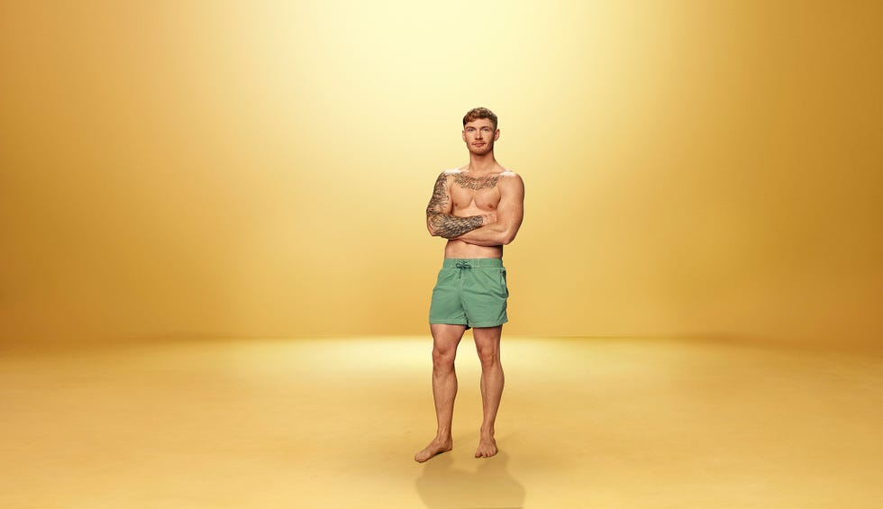 Jack Love Island barefoot individual in swim shorts against a golden backdrop