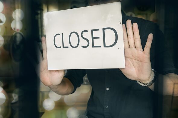 Man putting closed sign in window in shop Man putting closed sign in window in shop
