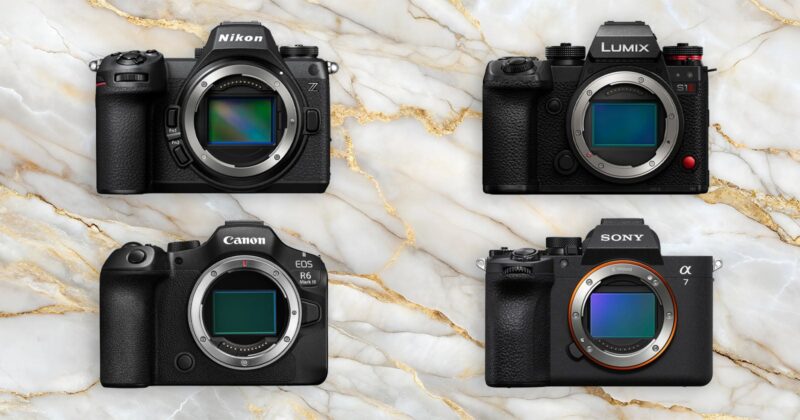 Four mirrorless camera bodies from Nikon, Lumix, Canon, and Sony are arranged in a grid on a marble background, each showing their lens mounts and sensors.