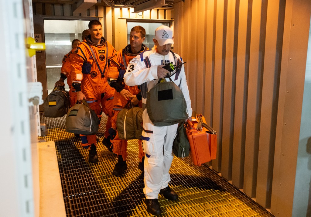 Bill Owens of the Closeout Crew leads the Artemis II crewmembers NASA astronauts Reid Wiseman, commander; Victor Glover, pilot; Christina Koch, mission specialist; and CSA (Canadian Space Agency) astronaut Jeremy Hansen, mission specialist; from the elevator at the 275-foot level of the mobile launcher to the crew access arm as they prepare to board their Orion spacecraft atop NASA’s Space Launch System rocket during the Artemis II countdown demonstration test, Saturday, Dec. 20, 2025, inside the Vehicle Assembly Building at NASA’s Kennedy Space Center in Florida. 