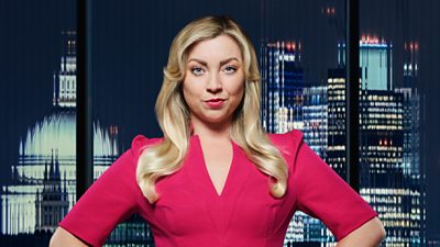 A blonde woman in a red dress poses outside a night-time city landscape