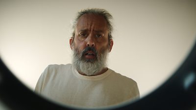 A man looks down directly to the camera. 