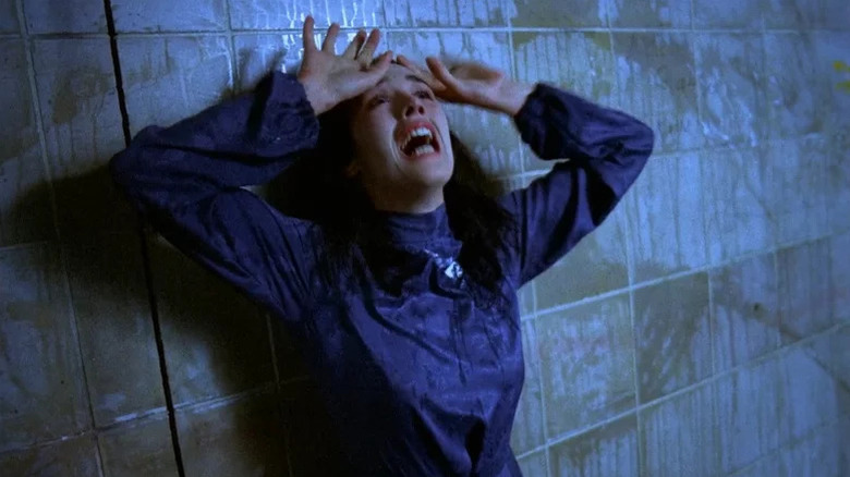 Isabelle Adjani as Anna looking distressed with hands on on her head in font of tiled wall in Possession
