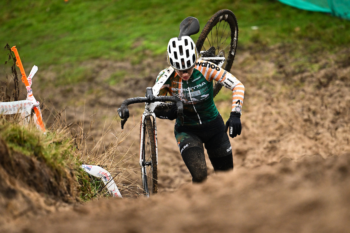 Woman carries bike up muddy hill