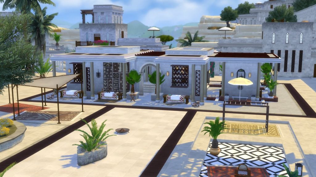 A modern desert-inspired courtyard features white stone buildings, shaded seating areas, patterned rugs, and palm trees under a bright blue sky.