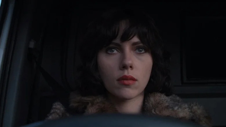 Scarlett Johansson as Lauren with dark hair, fur coat and lipstick driving vehicle in Under the Skin