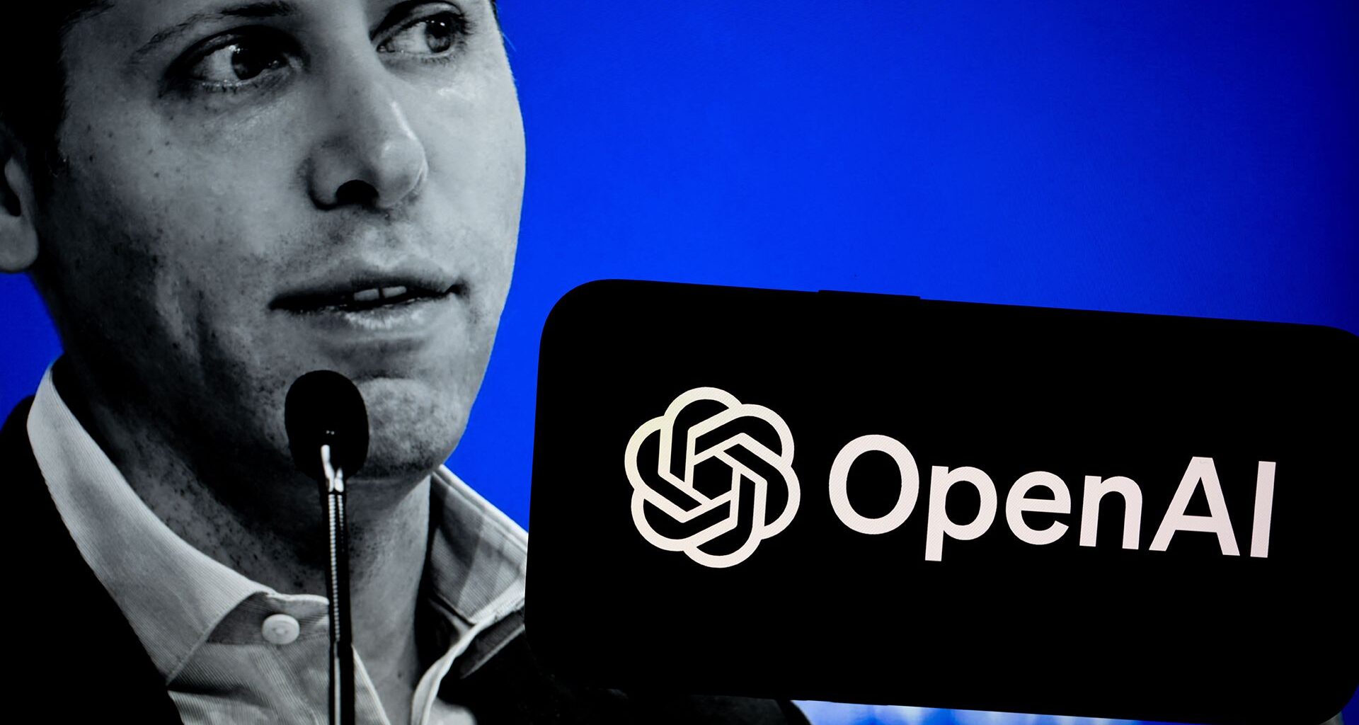 A black and white photo of Sam Altman, CEO at OpenAI, on a blue background with a phone bearing the OpenAI logo held in the foreground.