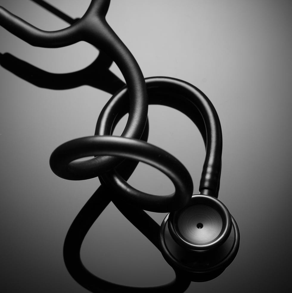 black stethoscope positioned on a reflective surface