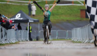 Woman crosses finish line on a bike with arms in the air