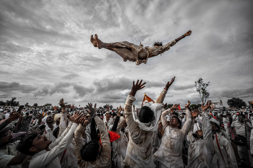 A man airborne above a crowd of people with their hands raised.