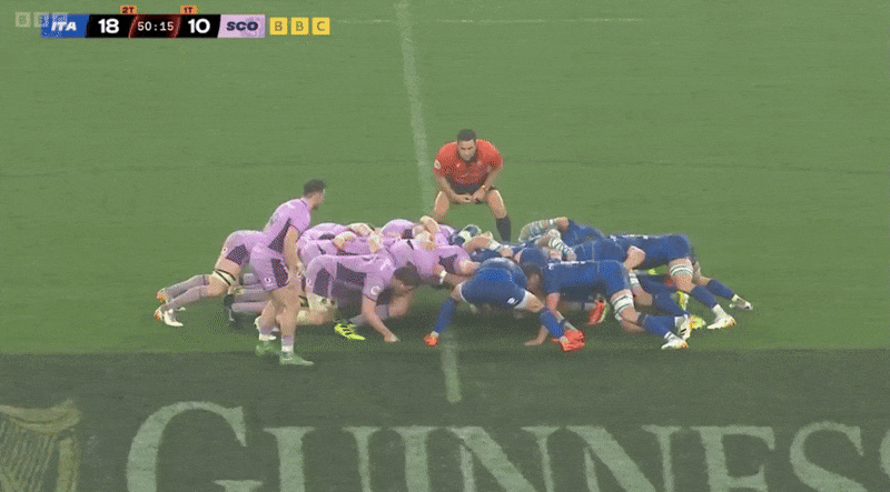 Rugby players from Italy and Scotland forming a scrum on the field.