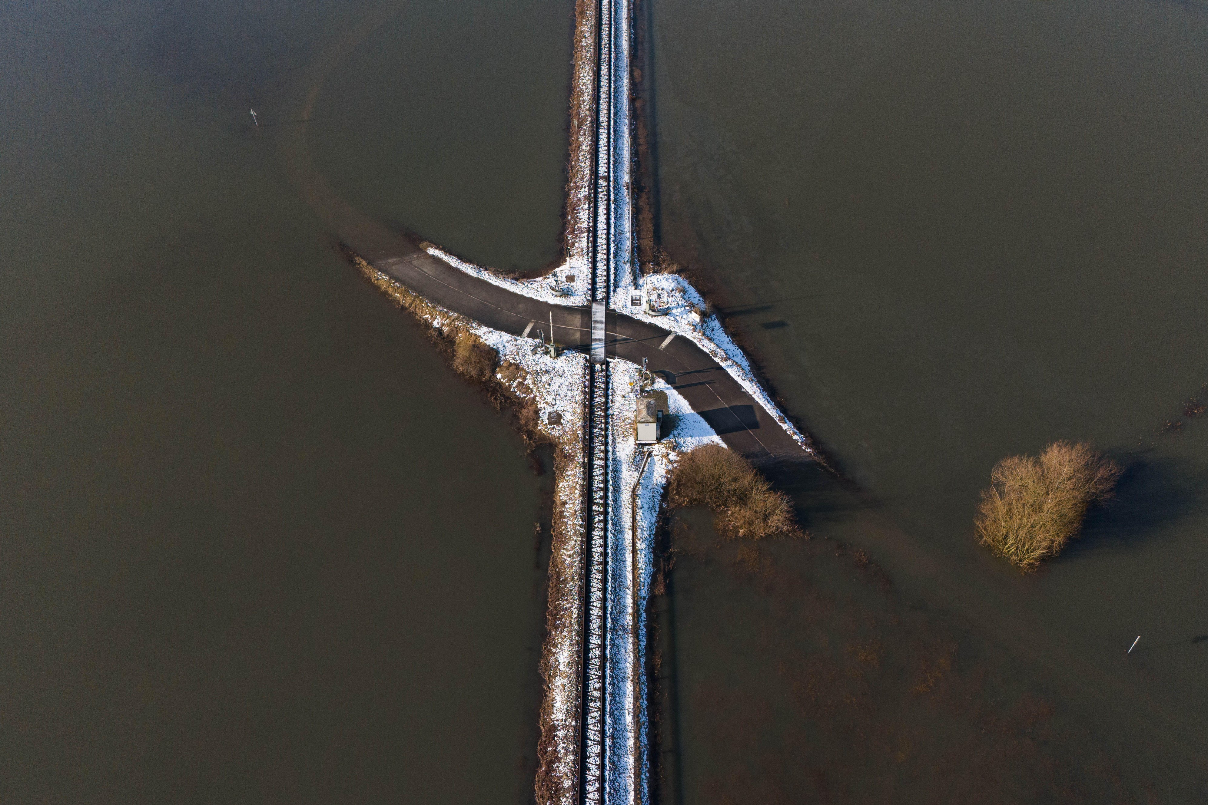 Train tracks amid flooded fields, partially covered in snow.
