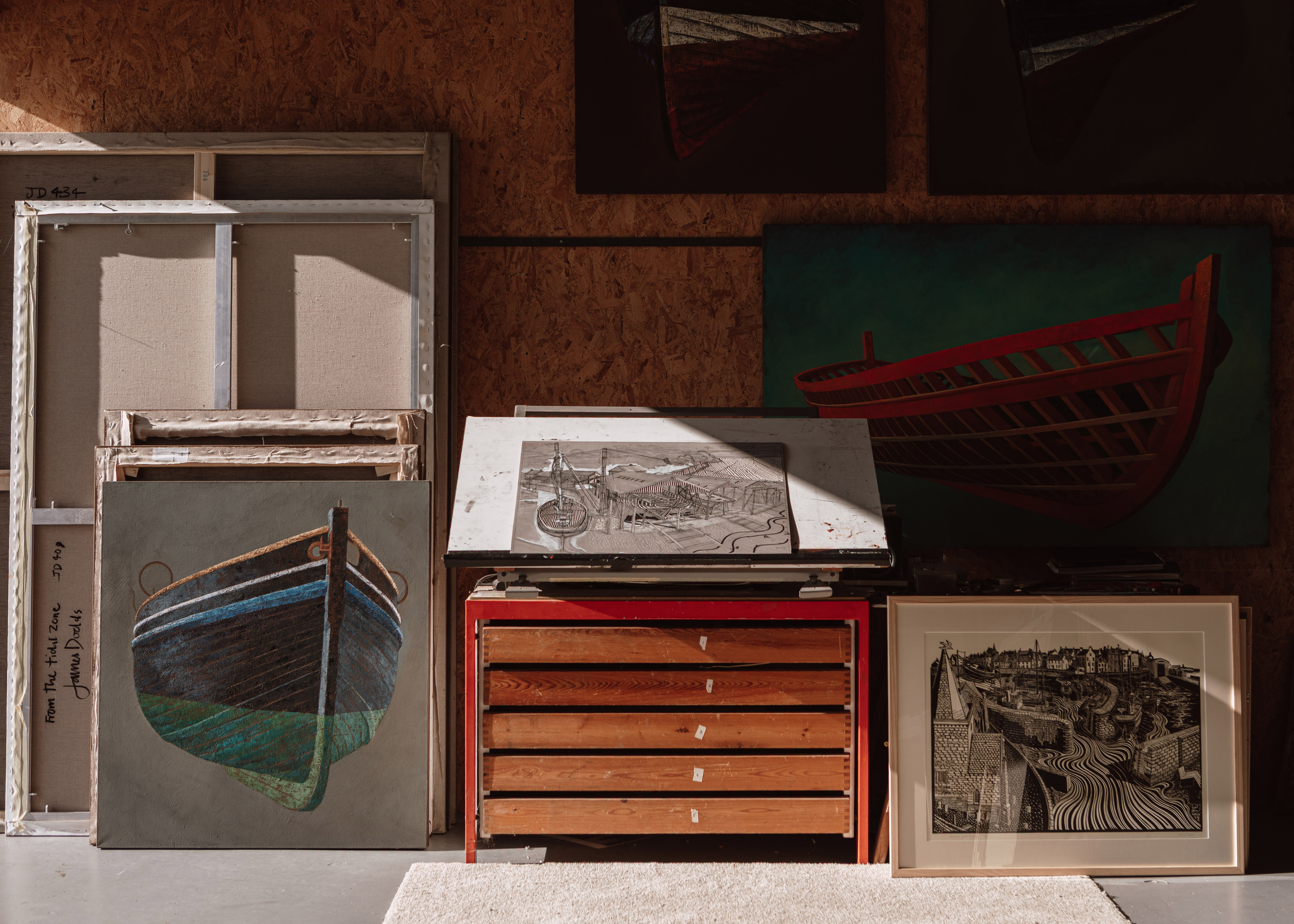 Artist James Dodds' studio space with paintings of boats and waterfront scenes.