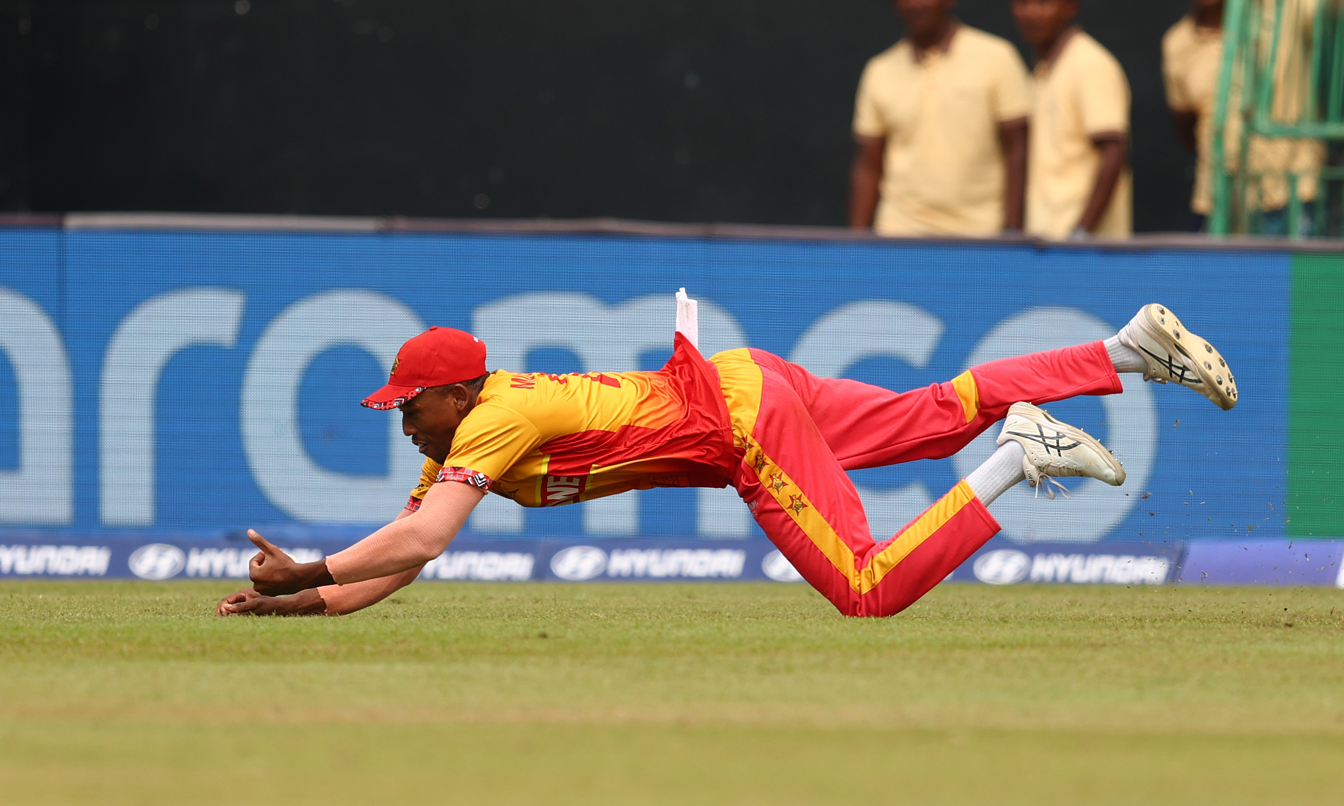 Tashinga Musekiwa of Zimbabwe diving to take a catch to dismiss Marcus Stoinis of Australia.