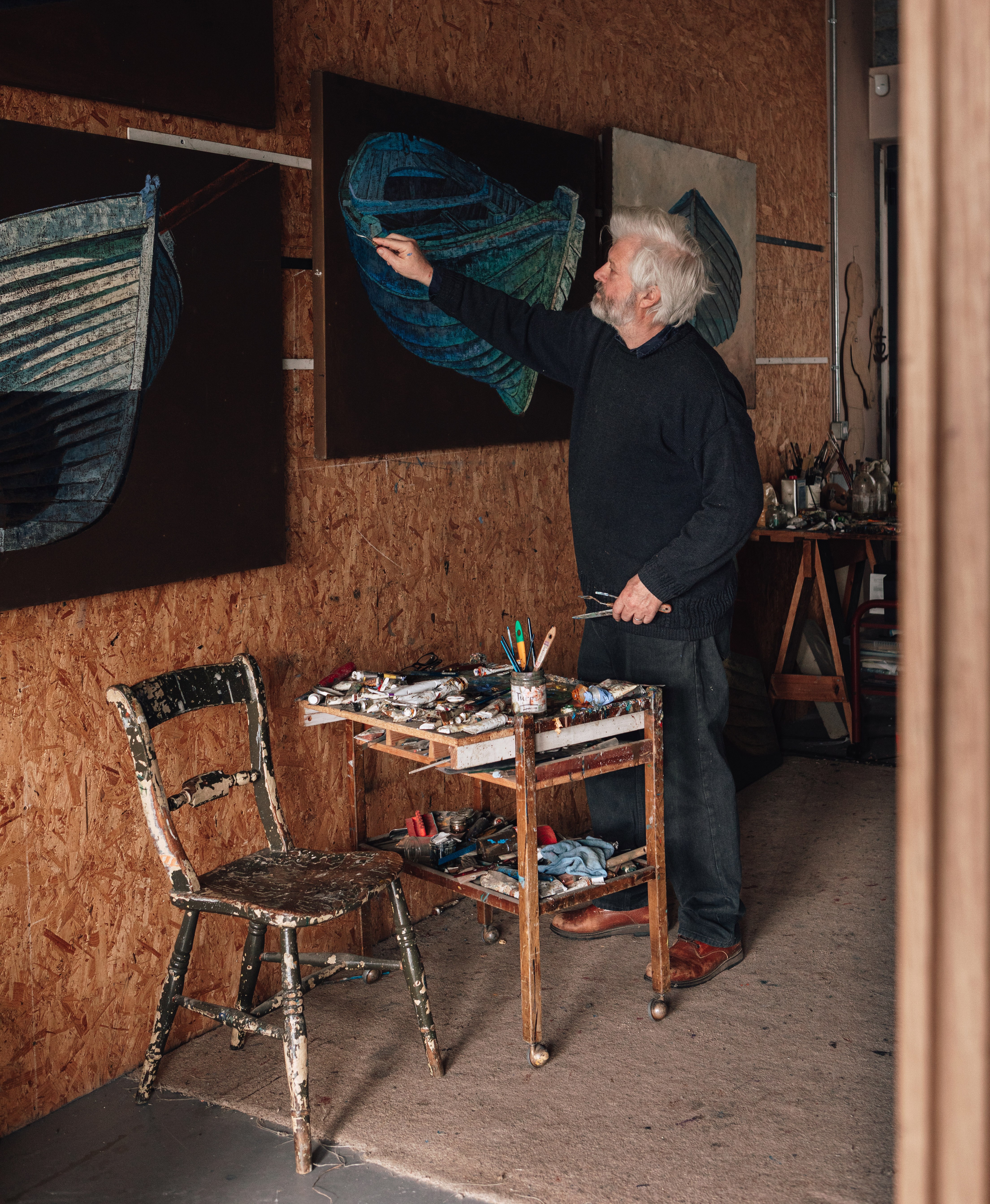 Artist James Dodds painting a boat on a canvas in his studio.