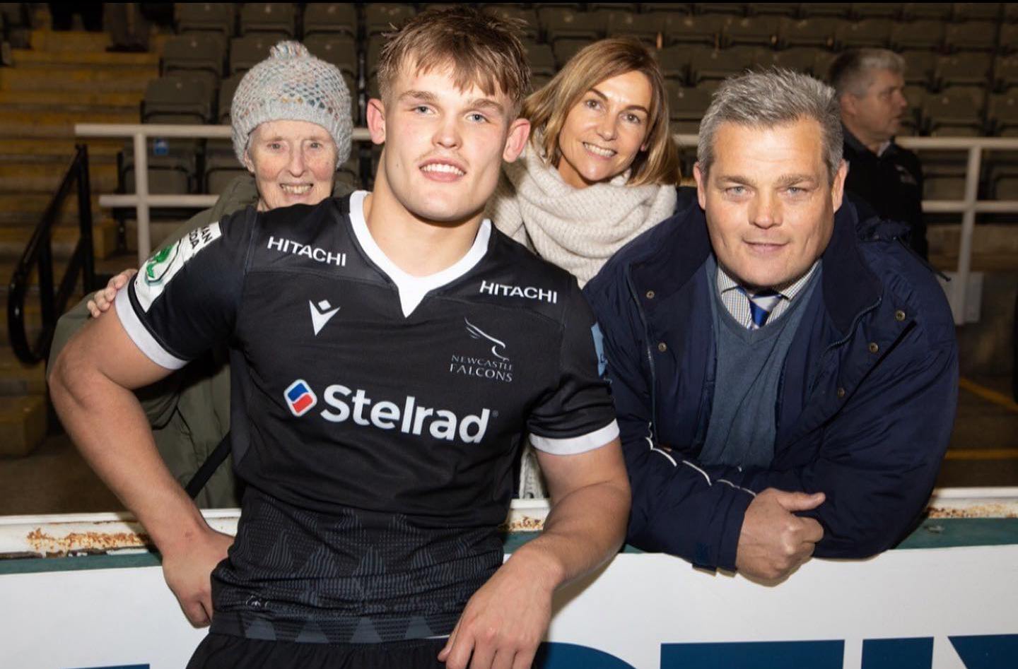 Guy Pepper posing with two women and a man in a stadium.