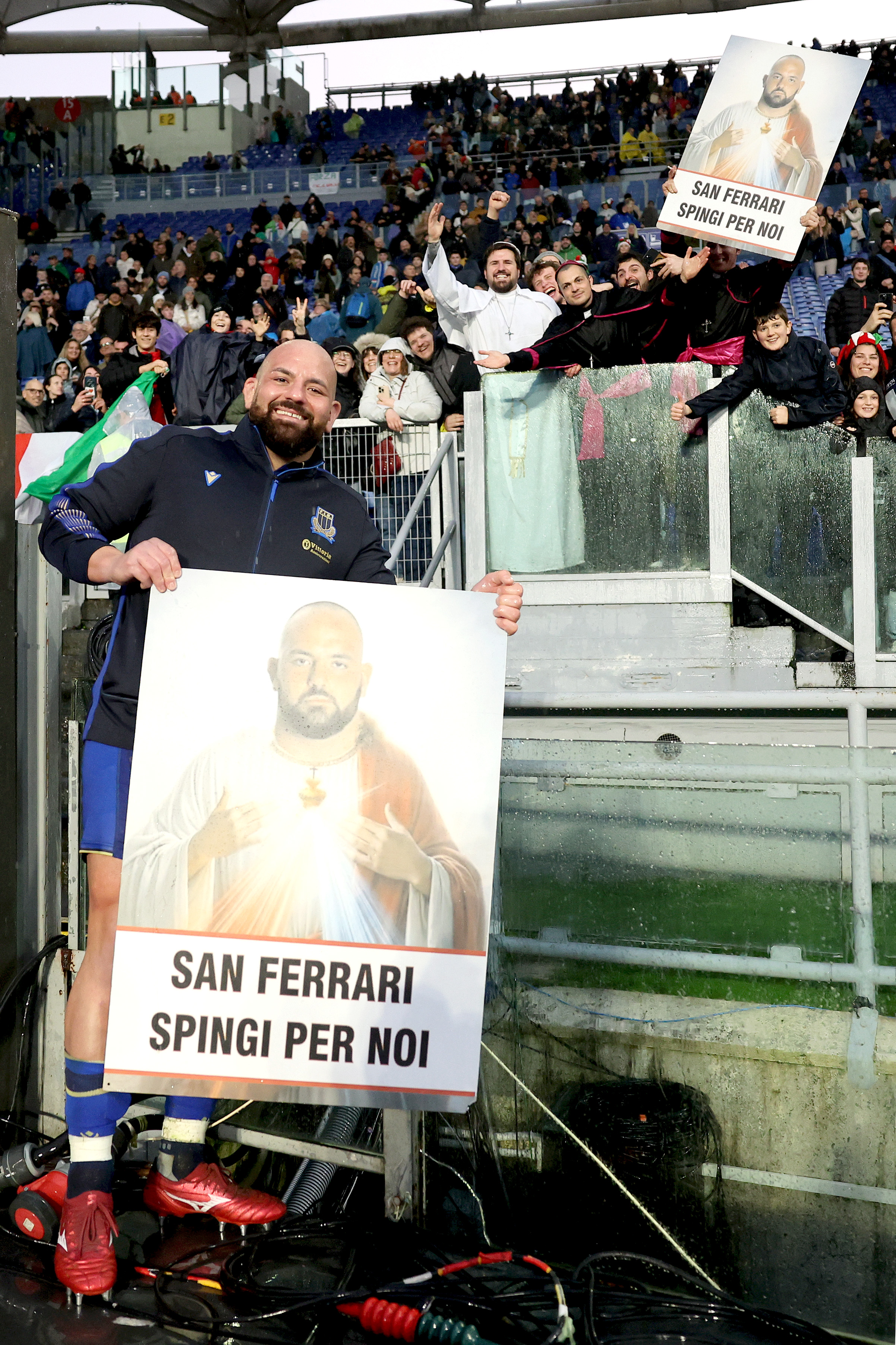 Rugby player Simone Ferrari celebrating with fans holding "San Ferrari" signs.