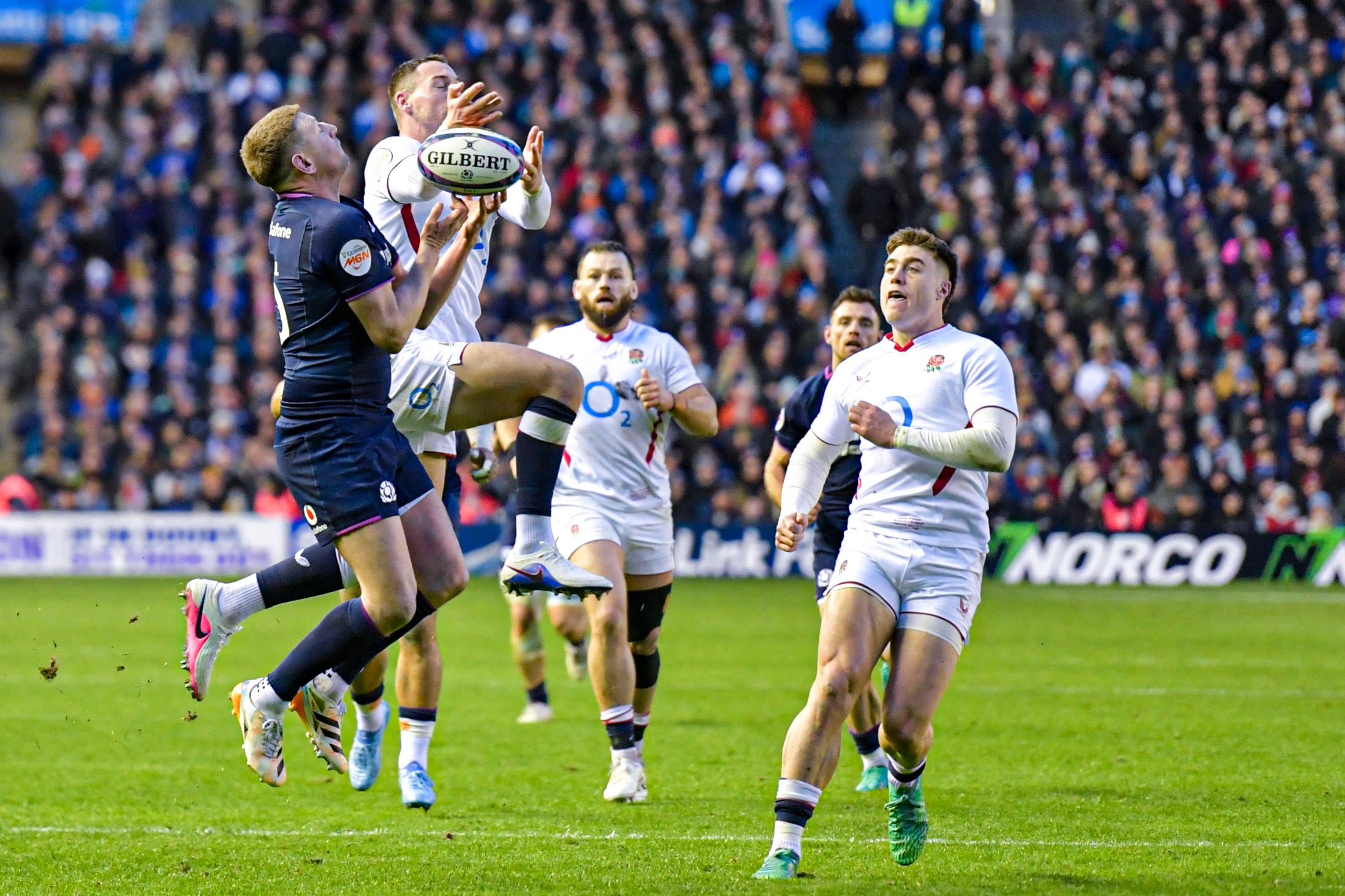 Finn Russell of Scotland and Ben Earl of England compete for the ball in the air during a rugby match.