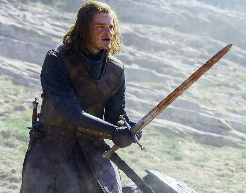 Robert Aramayo as young Ned Stark in Game of Thrones, holding a sword.