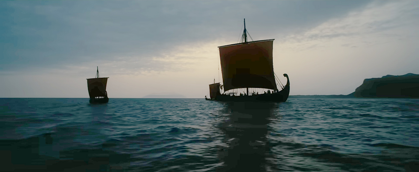 Two ancient ships with full sails on a cloudy sea.