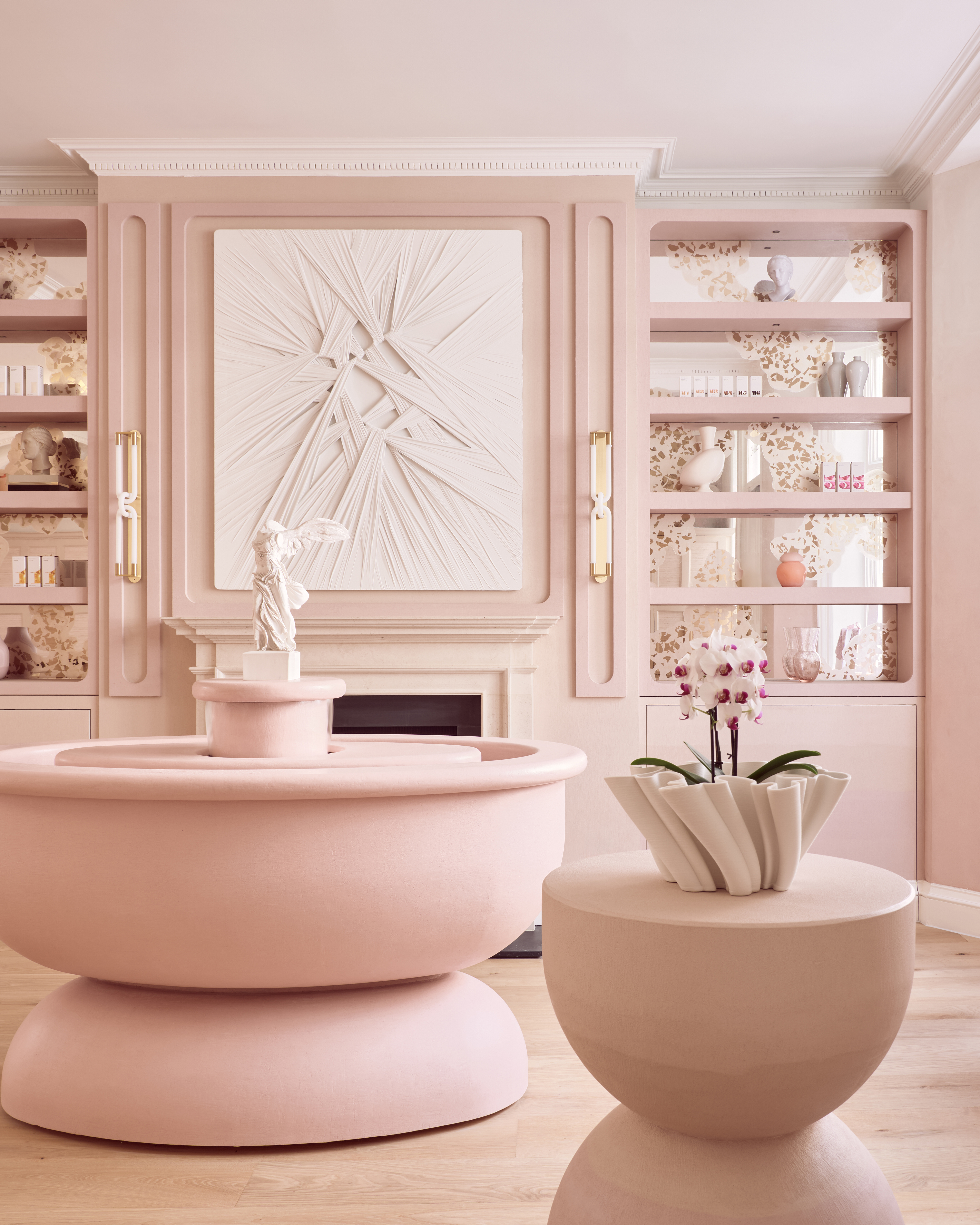 Interior of Dr. Joseph's clinic with blush pink walls, shelves, and a fountain, featuring a winged statue.