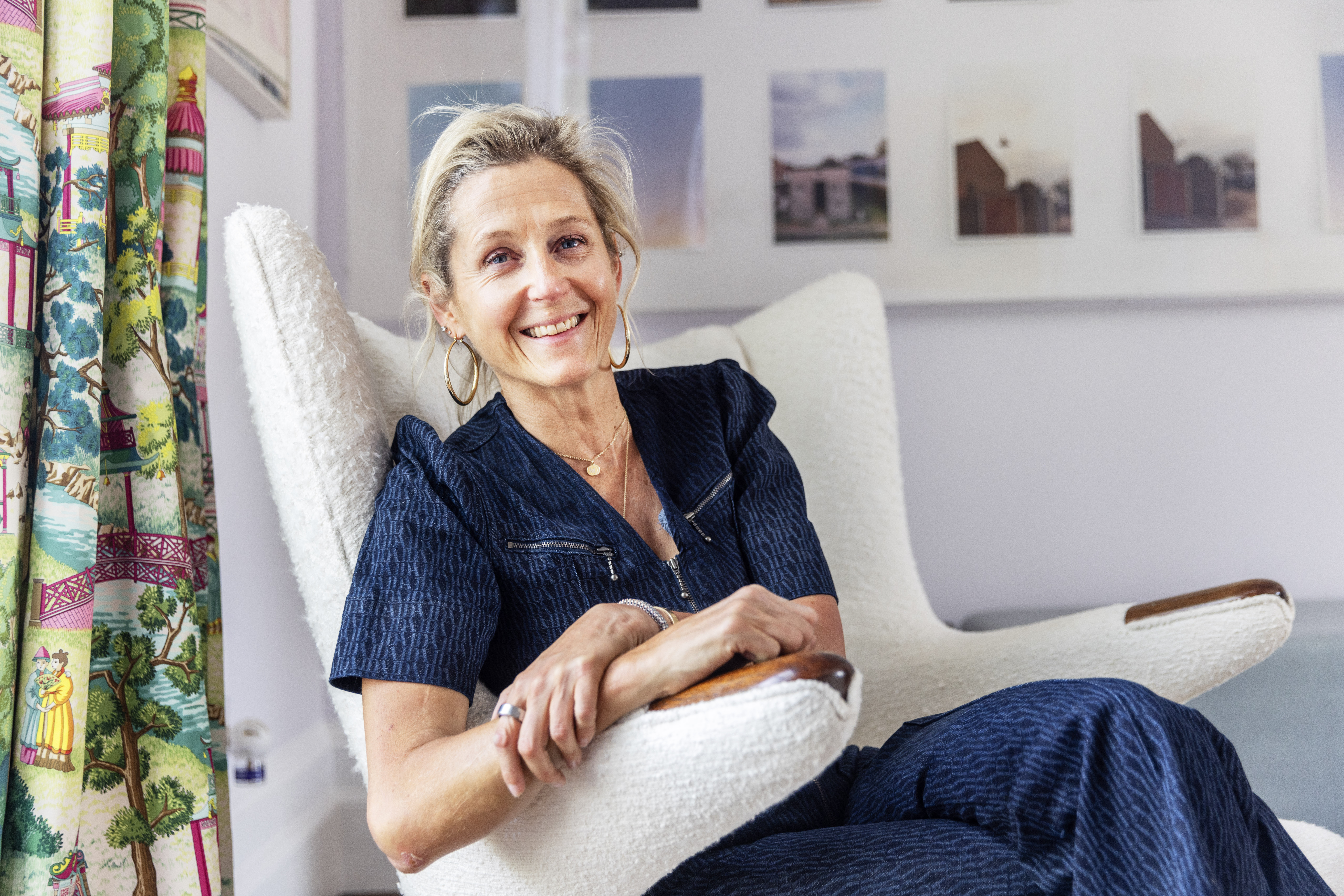 Martha Lane Fox smiles while sitting in a white armchair.