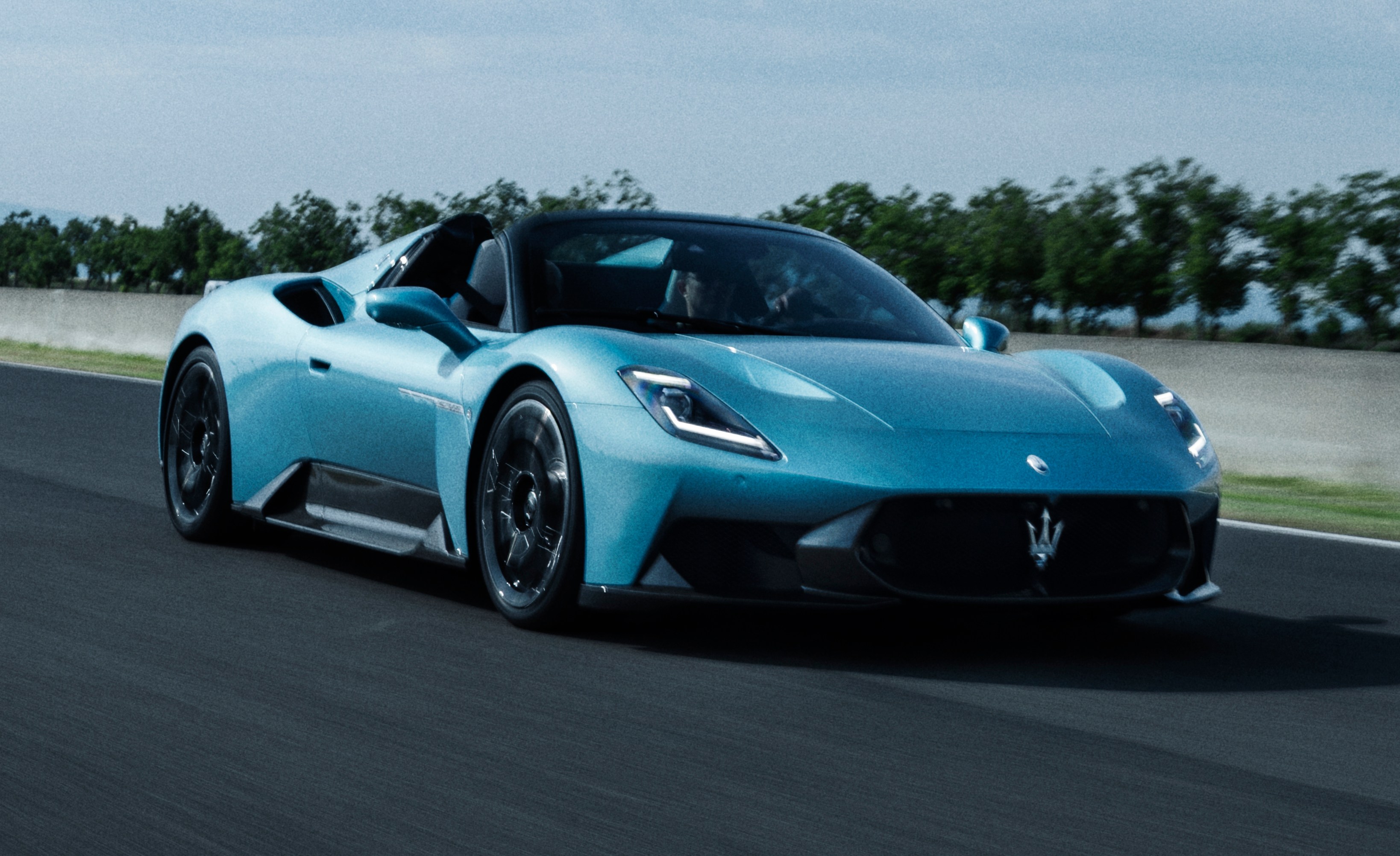 A light blue Maserati MC20 Cielo driving on a track.