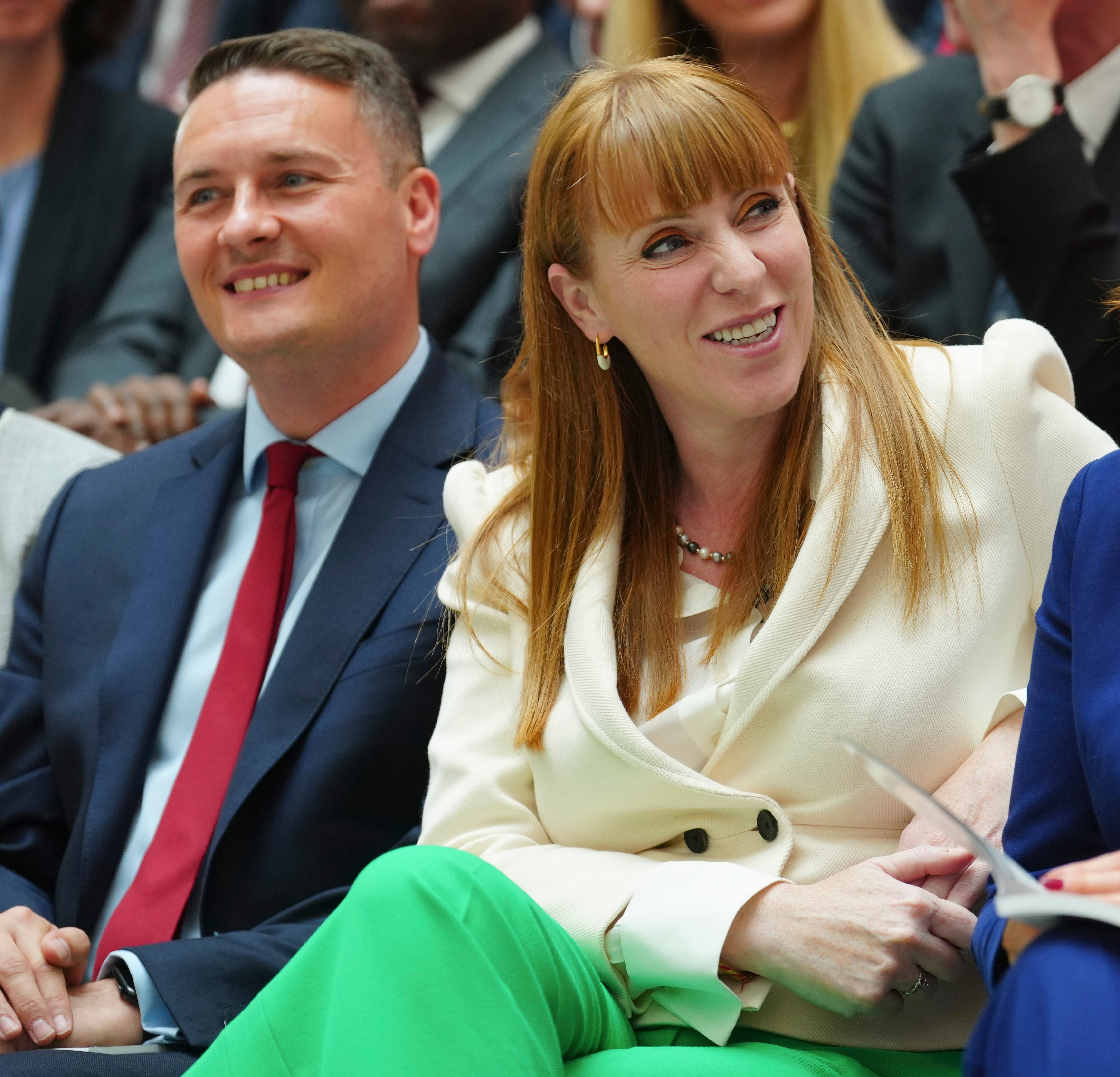 Four politicians smiling in the audience at the Labour party's 2024 general election manifesto launch.