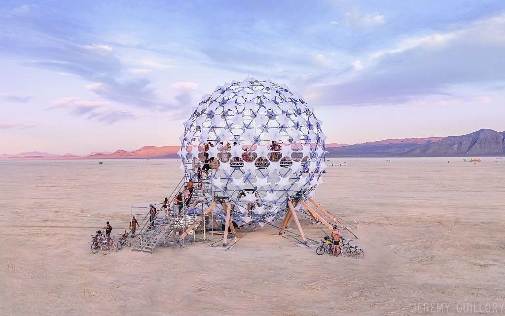 The Sonic Sphere, a 3D audio-visual venue at Burning Man, in the desert with people around it.