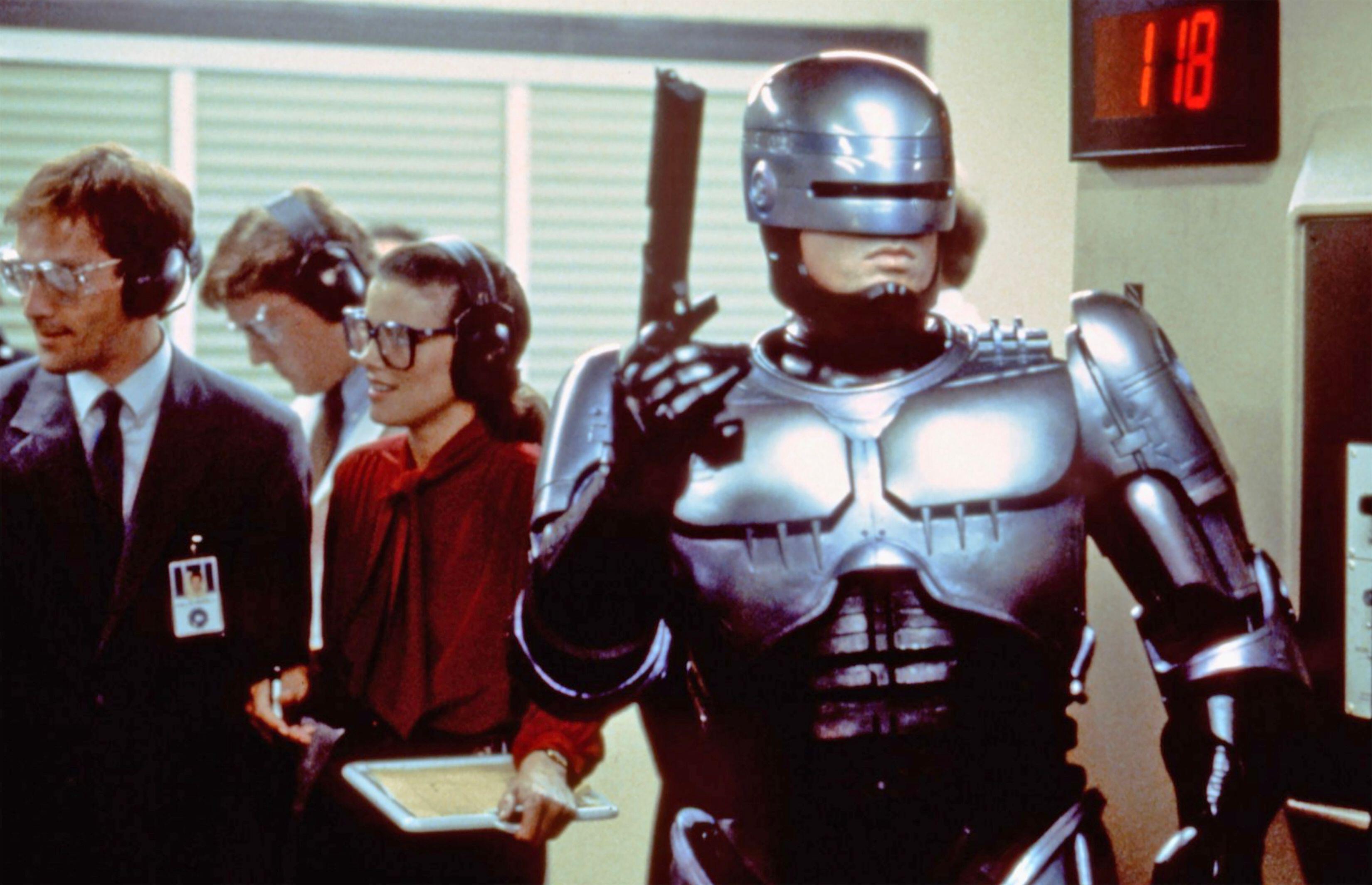 Peter Weller as Robocop holding a gun at a firing range.