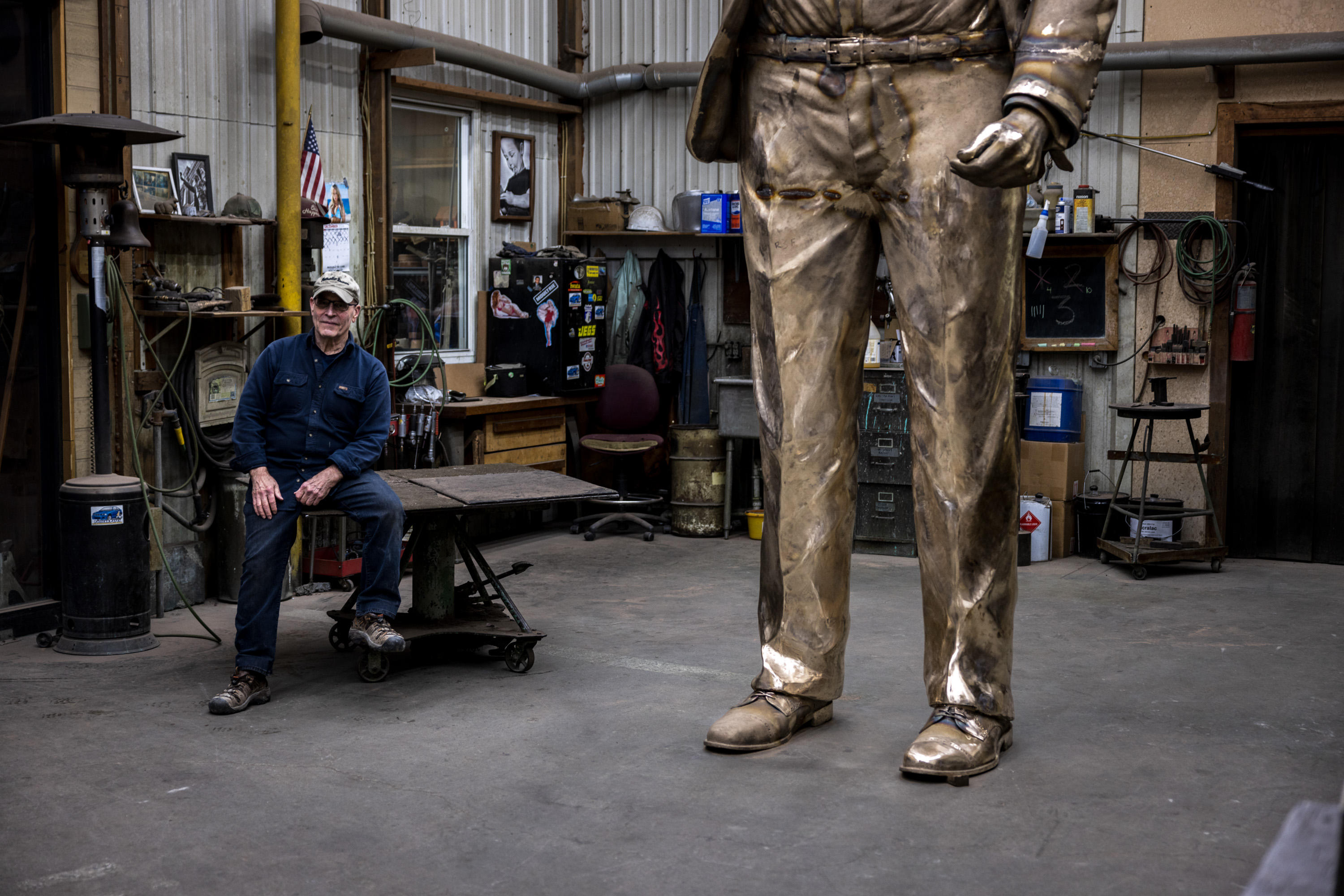 Alan Cottrill sitting next to his bronze sculpture.